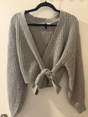 Grå knytbar stickad tröja - Sparsamt använd men inget synligt! Grå stickad tröja som går att knyta till ens preferens💕