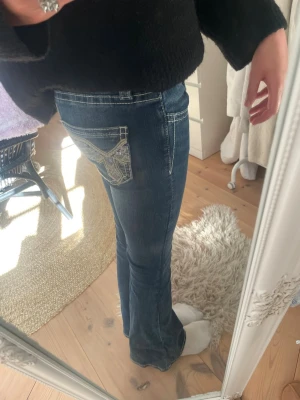 Blå bootcut jeans med detaljer  - Snygga blå low waist bootcut jeans från Gina. 36cm i midjemått rakt över och 83cm i innerbenslängd. Älskar jeansen men de kommer tyvärr inte till användning. Tryck gärna på köp nu!💛