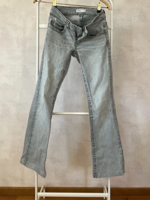 Ljusgrå bootcut jeans från Gina tricot - Säljer ett par ljusgrå bootcut jeans från Gina tricot. Jeansen har klassisk femficksmodell, låg midja och raka ben med lätt utsvängning. Tillverkade i mjukt denimtyg som ger en avslappnad look. Perfekta till sneakers eller boots.
