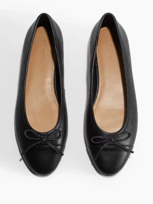 Svarta ballerinas från H&M - Stilrena svarta ballerinas från H&M med klassisk rund tå och en liten rosett framtill. Skorna är gjorda i ett slät mocka  med beige innersula och låg klack. Perfekta för dig som gillar enkel och tidlös design. Säljer pga att de inte kommer till användning 