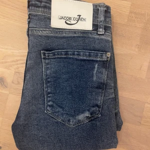 Blåa Jacob Cohen jeans  - Säljer ett par schysta vintage cohens i midja 31. Dem är i toppskick med snygga slitningar.                                                      Mått:                                                            Midja; 39cm.                                             Längd; 100cm.                                  Benöppning nere 14,5cm.                             Hör av er vid frågor eller prisförslag!