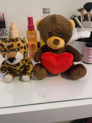 Gosedjur björn och leopard - Två mjuka gosedjur: en brun björn med ett rött hjärta och en leopard med gul och svartprickig päls. Perfekta som dekoration eller present till någon du tycker om. Båda är små och lätta att ta med sig.