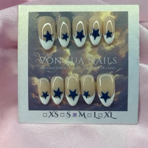 Obsessed (M);Medium Almond - Handgjorda press-on naglar i en medium lång mandelform med nude bas, handmålad vit fransk tippar och blå stjärnor. Snygg och trendig design som sticker ut. Perfekt för dig som vill ha unika naglar utan att gå till salong.M: 16 mm, 12 mm, 12,5 mm, 11,5 mm, 10 mm