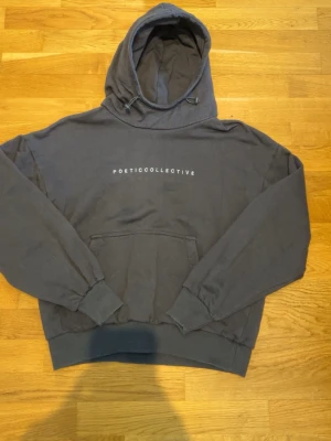 Svart hoodie från Poetic Collective - Svart hoodie från Poetic Collective med vit text på bröstet. Klassisk modell med huva och dragsko, samt stor magficka framtill. Mjukt material och ribbade muddar vid ärmslut och midja. Perfekt för en chill och stilren look. Köpt i butik för 500, använd vid ett fåtal tillfällen.
