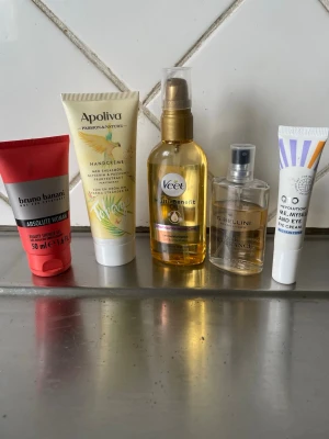 Skönhetspaket med krämer & olja - Ett kit med fem skönhetsprodukter: handkräm från Apoliva, bodylotion från Bruno Banani, olja från Veet, parfym från Bellini och ögonkräm från Revolution. Färgerna är blandade i gult, rött, vitt och guld. Perfekt för dig som gillar att testa olika märken.