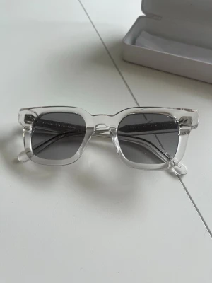  solglasögon från CHIMI - Snygga solglasögon från CHIMI med transparent, fyrkantig båge och mörktonade glas. Kommer med originaletui och box. Perfekta för dig som vill ha en clean och modern look. Har inte rört dem, dem har legat i lådan under längre tid