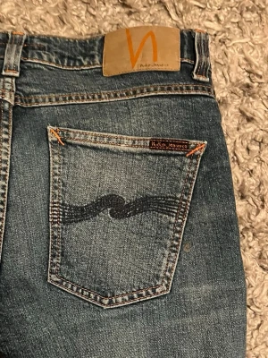 Blå slim fit jeans från Nudie Jeans - Säljer ett par riktigt feta nudies med slitningar. De är i storlek W27 L30 som passar runt 165/167! 👍tveka inte att fråga om extra bilder och priset är ej hugget i sten! 🙌