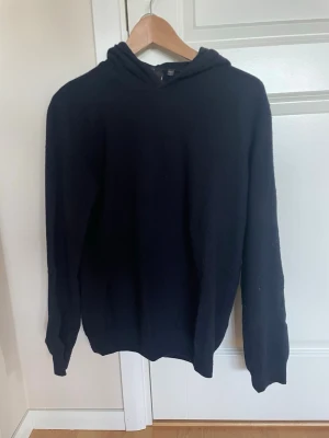 Marinblå hoodie från Oscar Jacobson - Klassisk marinblå hoodie från Oscar Jacobson, tillverkad i Italien. Litet hål i armhålan men inget man tänker på vid användning