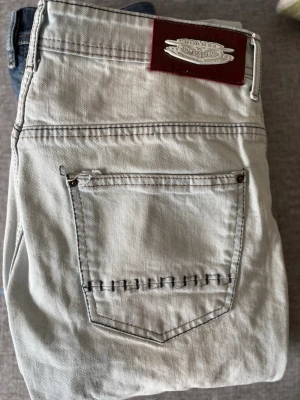 Ljusa slitna jeans från Dsquared2 - Säljer ett par ljusblå jeans från Dsquared2 med slitningar och trasiga detaljer på benen. Jeansen har klassisk femficksmodell, synliga sömmar och patch med logga bak i midjan. Perfekta för dig som gillar en edgy och trendig stil.