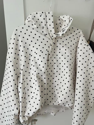 Prickig vit vindjacka med huva - Snygg vit vårjacka från gina tricot med svarta prickar och hög krage. Aldrig använd med lappen kvar🥹💐