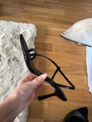 svarta klackar topshop - Snygga svarta pumps med spetsig tå och smala remmar. Skorna har ett glansigt ormskinnsmönster och en hög klack. Perfekta för dig som gillar trendiga och eleganta skor med en edgy touch.