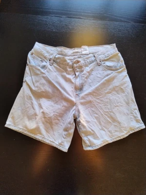 Vita denimshorts från Levi's - Vita denimshorts från Levi's., knappgylf och raka ben. Shortsen är tillverkade i bomull, vilket ger en avslappnad och tidlös look. 90cm midja