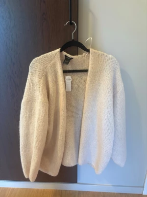Beige stickad kofta från Lindex - Mysig beige stickad kofta från Lindex! Helt ny med prislapp