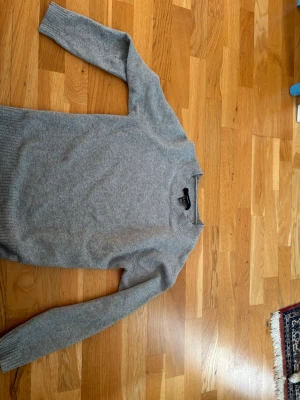 Grå stickad tröja från Vera moda - Den trendiga tröjan får Vero moda. Mjuk och enkel grå stickad tröja från Vera moda med rund halsringning och långa ärmar. Tröjan har ribbade muddar vid ärmslut och nederkant. Perfekt basplagg i garderoben och passar till det mesta. Materialet känns lent och bekvämt.