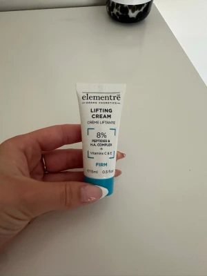 Elementré Lifting Cream 15ml - Elementré Lifting Cream är en ansiktskräm i en vit och blå tub på 15 ml. Innehåller 8% peptider och H.A. complex samt vitaminerna C och E. Tuben är smidig att ta med och har en modern design. Perfekt för dig som vill ha en uppstramande effekt. Aldrig använd! Nypris 125kr/10ml 