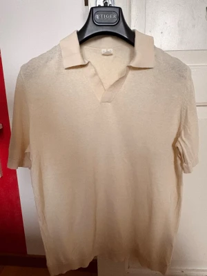 Pikétröja hm strl S - Stilren beige pikétröja från HM med klassisk krage och v-ringad öppning. Tillverkad i mjukt material som känns skönt mot huden. Perfekt för dig som gillar en enkel men snygg look.