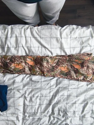 Mönstrade jeans från Mos Mosh - Säljer ett par unika jeans från Mos Mosh med coolt djurmönster i brunt, grönt och orange. Byxorna har gylf med dragkedja och knapp, samt detaljer i guld. Perfekta för dig som vill sticka ut med din stil!