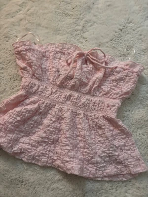 Ljusrosa smockad linnetopp med knyt - Säljer denna supersöta toppen från Gina tricot. Toppen är endast använd en gång och är som ny, i stolek S men man kan även anpassa den efter sig själv då snöret upptill går att dra åt för att spänna toppen som man vill. 💗💗