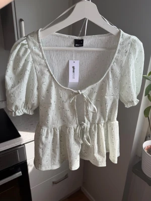 Kortärmad topp - Söt topp från GinaTricot, 2 knyten fram. Mintfärg 💚 Ena klädbandet (sista bilden) har lossnat men ingenting som påverkar utseendet av plagget  Storlek; XS Skick; Ny med prislapp Material; 98% polyester, 2% elastan  #sommar #topp #blommig #scandi #ginatricot