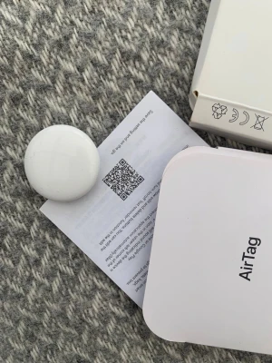 Apple AirTag spårningsbricka - Säljer en vit Apple AirTag, perfekt för att hålla koll på dina prylar. Kommer med originalförpackning och instruktioner. AirTag är rund och kompakt, tillverkad i plast och metall, och kopplas enkelt till din iPhone för smidig spårning.