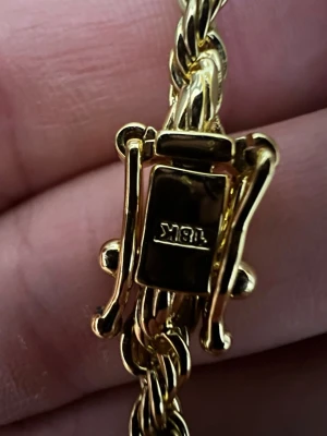 Guldpläterat cordel  18K - Snyggt flätat armband i 18 karat guld med elegant låsdetalj. Armbandet har en klassisk guldfärg och känns både stilrent och lyxigt. Perfekt accessoar för dig som gillar tidlös design och vill addera lite extra bling till din look.