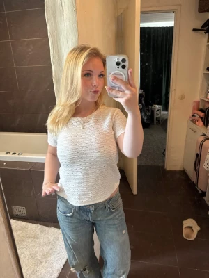 Mönstrad t-shirt från Zara - Säljer en vit stickad topp med korta ärmar och rund hals. Toppen har ett snyggt mönster och är perfekt för dig som gillar en enkel men ändå trendig stil. Passformen är normal och materialet känns mjukt och luftigt.