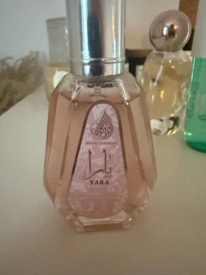 Yara parfym 50ml Ard Al Zaafaran - Yara parfym från Ard Al Zaafaran i en elegant, multifacetterad glasflaska med rosa etikett och silverfärgad kork. Flaskan rymmer 50 ml och har en feminin, modern design som sticker ut på parfymhyllan.