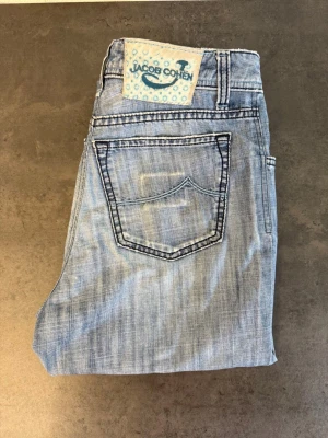 Ljusblå jeans från Jacob Cohen W34 UNISEX - Snygga ljusblå jeans från Jacob Cohen med klassisk femficksmodell och raka ben. Jeansen har en cool tvättad look och kontrastsömmar. Tillverkade i mjukt denimtyg som ger en avslappnad och trendig stil.
