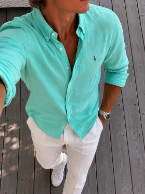 Turkos / mint skjorta från Ralph Lauren - Säljer en fräsch turkos skjorta från Ralph Lauren. Skjortan har klassisk button-down krage, långa ärmar och den ikoniska broderade loggan på bröstet. Perfekt för dig som gillar en stilren och avslappnad look.
