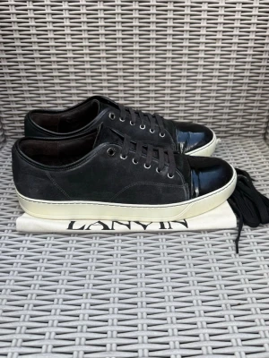 Svarta Lanvin sneakers med lackdetalj - Lanvin Cap Toe || Storlek 43 || Skorna är i mycket bra skick (se bilder) || Dustbag & extra skosnören medföljer || Tveka inte på att höra av dig vid frågor eller funderingar 