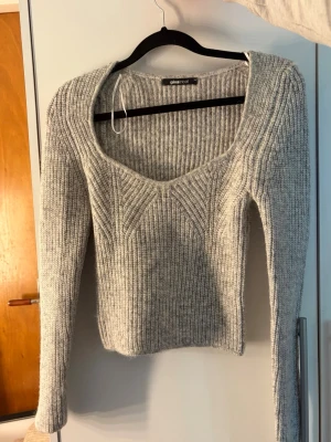 Grå ribbstickad tröja Gina Tricot - Säljer en grå ribbstickad tröja från Gina Tricot med djup, rundad halsringning och snyggt mönster framtill. Tröjan har långa ärmar och är något croppad i modellen. Perfekt för en vardag och ute kväll. Aldrig använd bara prova den och dragit av prislappen, Priset kan diskuterass