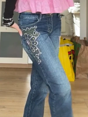 Blå jeans med broderade fjärilar - Säljer ett par blå jeans med snygga broderade fjärilar Perfekta för dig som vill ha en unik och trendig look. Storlek W27 L32,5 vilket motsvarar S/36