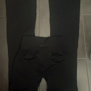 Svarta utsvängda träningstights från aim'n - Säljer ett par svarta utsvängda träningstights från aim'n med reglerbar midja och stretchigt material. Perfekta för gymmet eller löpning. Snygg och enkel design med liten logga framtill. Köpt för 600kr. Pris kan diskuteras