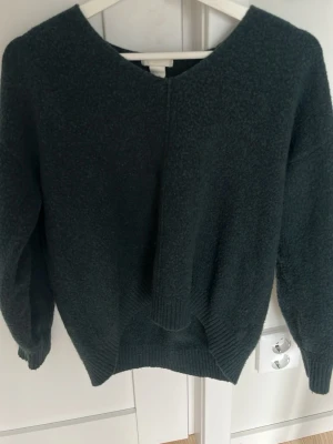 Mörkgrön stickad tröja med V-ringning - Jätte fin mörkgrön stickad tröja från HM. Sticks inte och är lite kortare vid magen än i ryggen. Jätte snyggt med ett par lågmidjade jeans. Perfekt för en sommarkväll!