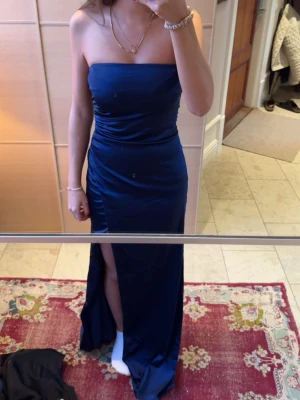 Marinblå axelbandslös långklänning - Snygg marinblå axelbandslös långklänning med slits framtill. Aldrig andvänd och har lappen kvar💗nypris 799!
