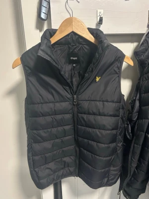 Lyle & Scott väst - Svart dunväst från Lyle & Scott.                                       Den är storlek 12-13 år vilket är samma som xs.