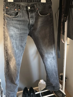 Grå Levi's 501 jeans vintage fit - Säljer ett par grå Levi's 501 jeans med klassisk rak passform och fem fickor. Jeansen har en snygg tvättad look och är tillverkade i slitstark bomull. Perfekta för dig som gillar en tidlös och avslappnad stil.
