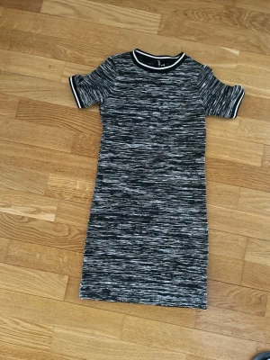 Svartvit randig kort klänning H&M - Kort klänning från H&M i svartvitt randigt mönster. Klänningen har rund halsringning med kontrastkant och korta ärmar. Materialet är mjukt och stretchigt, perfekt för en avslappnad men snygg look.