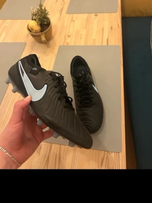 Nike Tiempo Elite ag - Säljer ett par svarta Nike Tiempo fotbollsskor med klassisk vit swoosh på sidan. Skorna har snörning, låg profil och dobbar för spel på gräs. Tillverkade i syntetmaterial med stilren design som passar perfekt för matcher och träning. Använda 3 gånger storlek 44 har ingen elite påse eller box med tyvärr. Buda så fort du ser annonsen behöver få sålt dem så snabbt som möjligt!