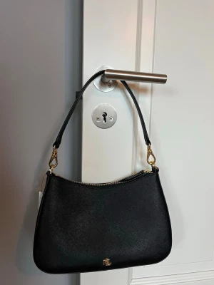 Ralph Lauren väska - Vill sälja denna väska då mamma köpte den utan att kolla med mig så den kom tyvärr inte till användning. Prislappen är kvar och den är aldrig använd. Köpte den för 3095kr på Zalando. Tryck gärna på köp nu!🫶🏼