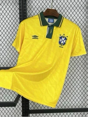 Gul Brasilien fotbollströja Umbro - Klassisk gul Brasilien fotbollströja från Umbro med gröna detaljer på kragen och blått CBF-märke på bröstet. Tröjan har korta ärmar, pikékrage och tryckt Umbro-logga. Perfekt för dig som älskar fotboll och vill visa ditt stöd för Brasilien.