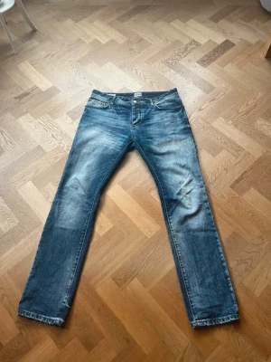 Vintage jack and Jones jeans - Säljer ett par blå jeans med raka ben och snygga slitningar framtill och baktill. Jeansen har klassisk femficksdesign och normal midja. Perfekta för en avslappnad och trendig look.