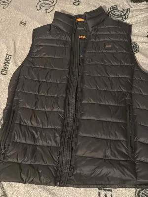 Svart dunväst från BOSS - Snygg svart dunväst från BOSS med quiltad design och hög krage.