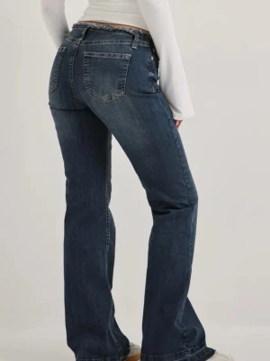 Mörkblå bootcut jeans - Snygga mörkblå bootcut jeans med klassisk femficksdesign och normal midja. Jeansen har en lätt tvättad look och raka ben som går ut något nedtill. Perfekta till sneakers eller boots för en avslappnad stil.