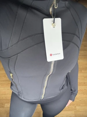 Svart träningsset från Lululemon - Snyggt svart träningsset från Lululemon med figurnära passform.🖤 Jackan har dragkedja framtill, höga fickor med dragkedja och tumhål vid ärmsluten.🖤 Materialet är stretchigt och följsamt, perfekt för gym eller yoga🔥                                 ‼️OBS‼️- Jag har i både storlek 6 & 4, storlek 4 = xxs/xs & storlek 6 = xs/s