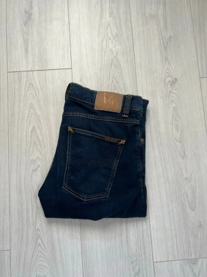 Mörkblå jeans från Nudie Jeans - Säljer dessa sjukt snygga jeans från Nudie! Då jag endast använt dom ett få tal gånger så är de i topp skick. Modellen är 170 cm lång och väger 72 kg, köptes via jeansbolag i Falun för 1440 kr. Strl: W30 L32. Modellen på jeansen är Lean Dean. 