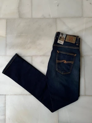 Mörkblå jeans från Nudie Jeans - Grim Tim - Säljer ett par sjukt snygga Nudie Jeans i storleken 30-32 som är helt nya med prislapp! 😁——————————————————————————                                                          📐| Storlek: 30-32                                                  👖| Märke: Nudie jeans                                         🔎| Skick: Nytt skick                                              💵| Ny Pris: 1699kr                                                   ✍🏻| Skriv om du har några frågor
