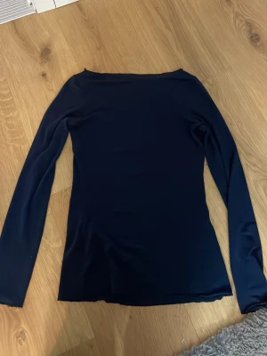 Mörkblå långärmad topp - En stilren mörkblå långärmad topp med enkel, rak passform. Perfekt att matcha med jeans eller kjol för en clean look. Tunn och mjuk i materialet, vilket gör den skön att bära hela dagen.