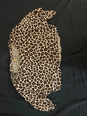 Leopardmönstrad mesh topp oneshoulder - Säljer en leopardmönstrad mesh topp med oneshoulder-design. Toppen har asymmetrisk nederkant och är tillverkad i ett tunt, stretchigt material som ger en cool och edgy look. Perfekt för dig som vill sticka ut med ett djurmönster.