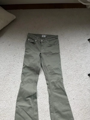 Olivgröna bootcut jeans från 157 - Snygga olivgröna jeans från 157 med bootcut passform. Klassisk femficksmodell och normal midja. Jeansen har en stilren look och är tillverkade i ett mjukt bomullsmaterial med lite stretch för extra komfort.